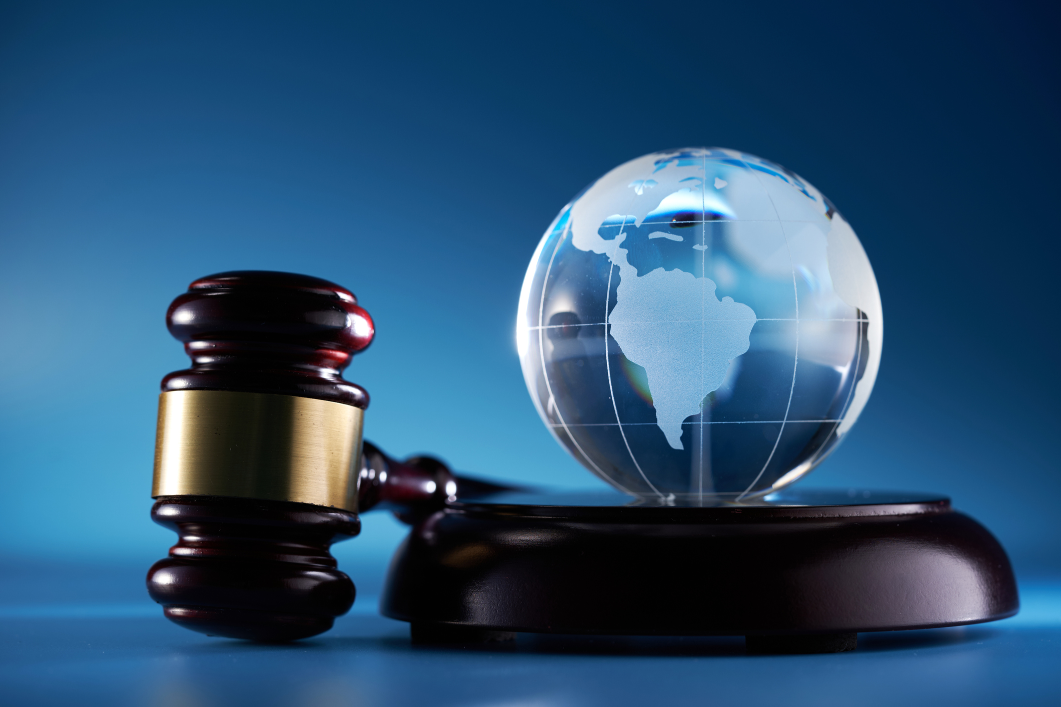 gavel hammer and glass globe against blue background golden-icon-with-scales-of-justice-and-text-legal-concept